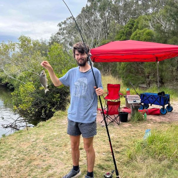 A participant proudly showing his catch on a riverside fishing day